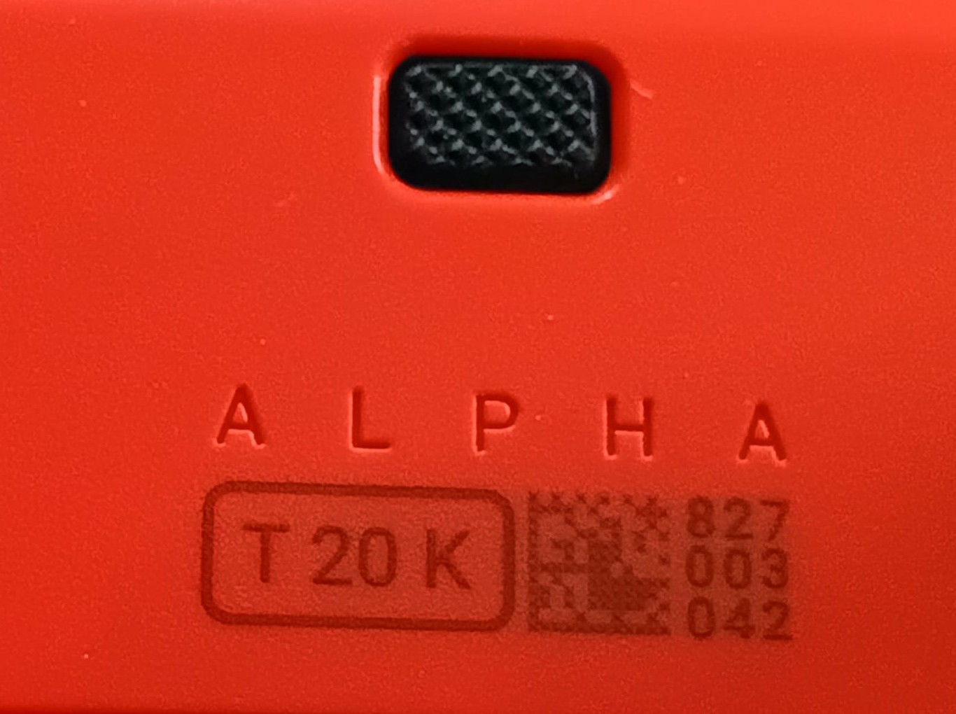 Close-up of a red device with the embossed word ALPHA and a rounded label reading T20K.
